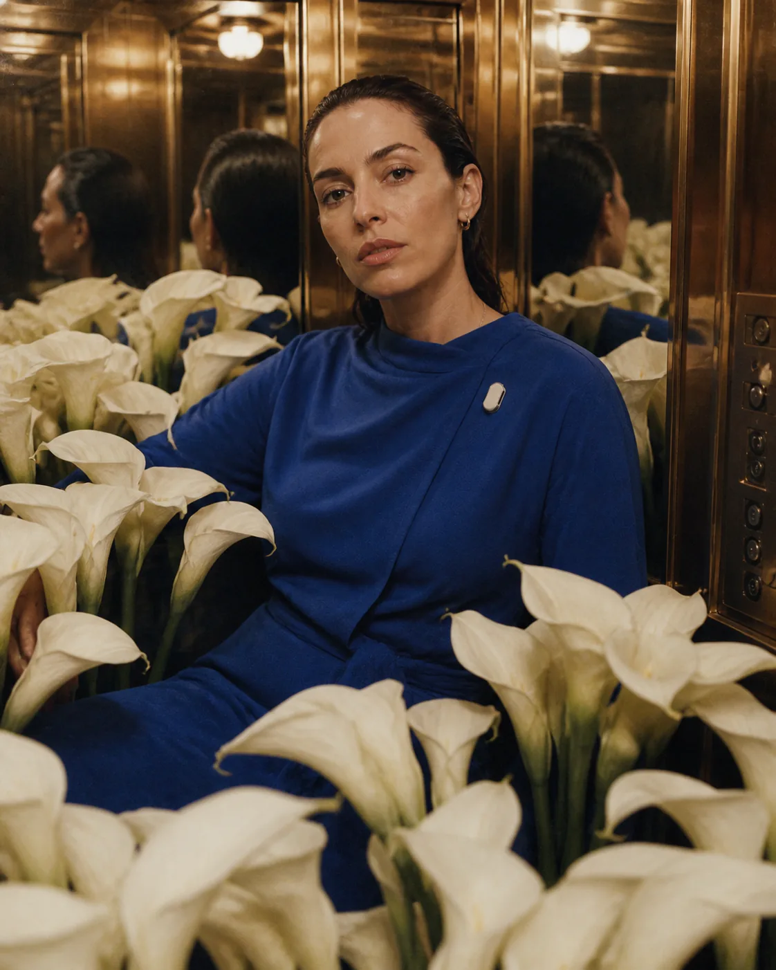 Person in cobalt blue wearing Presence Key among white calla lilies