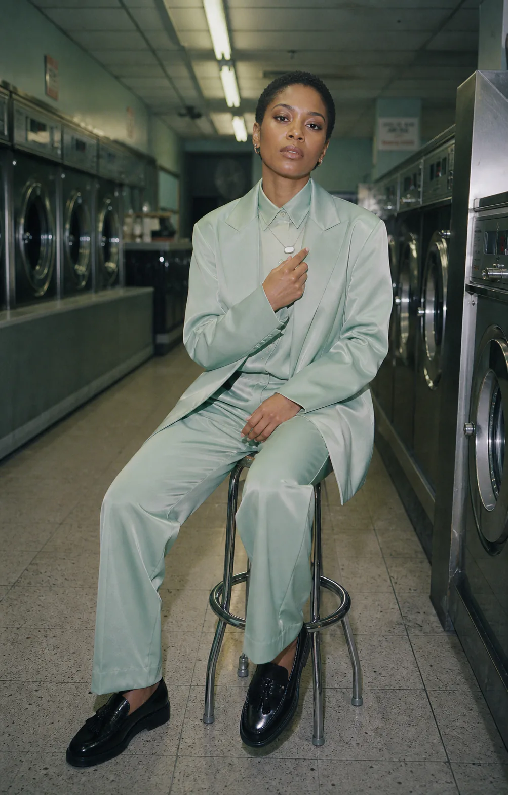 Woman wearing Presence Key over a mint suit in a laundrette