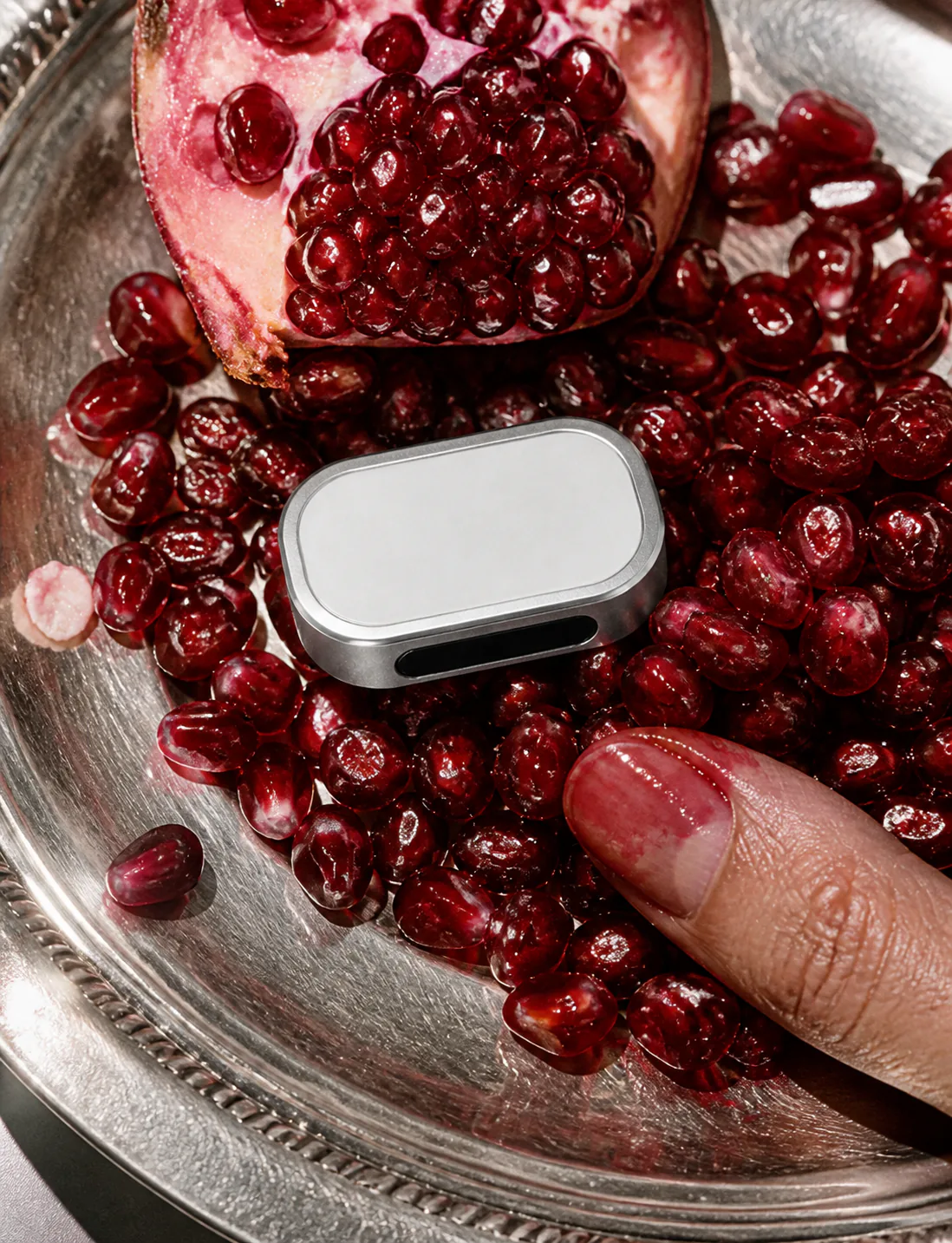 Silver Presence Key placed among deep red pomegranate seeds