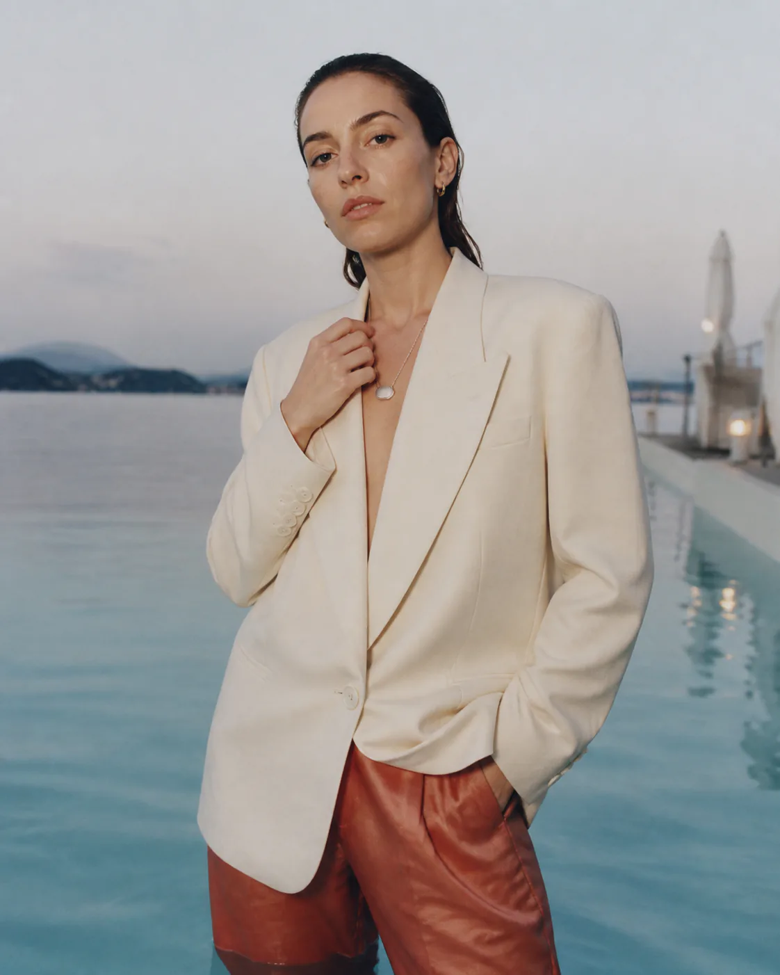 Woman wearing an ivory Presence Key pendant beside a pool at dawn